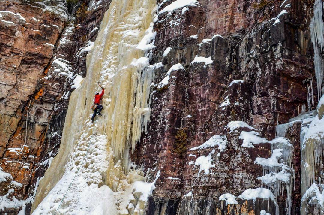 A man ice climbing a tall frozen waterfall