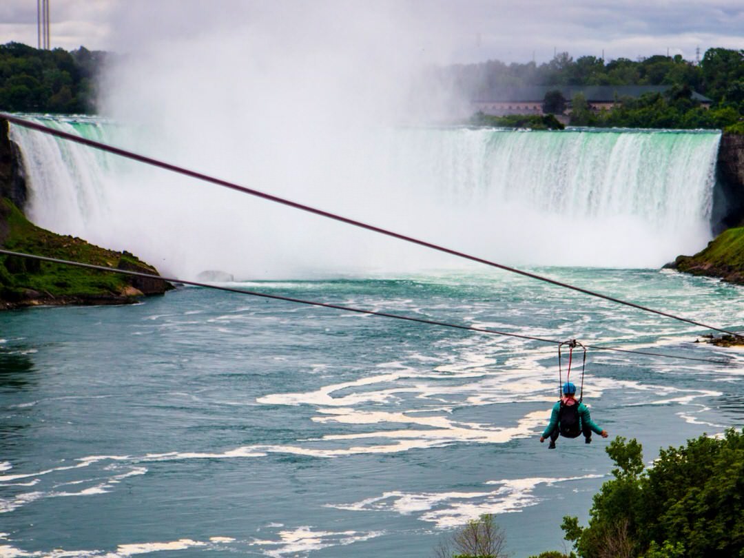 A person zip lining in front of the Niagara Falls
