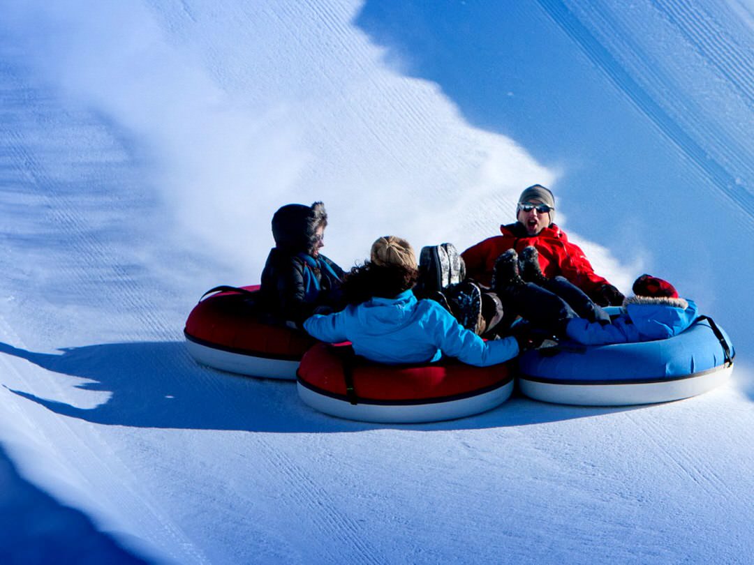A family of four having fun sliding down a snowtubing run