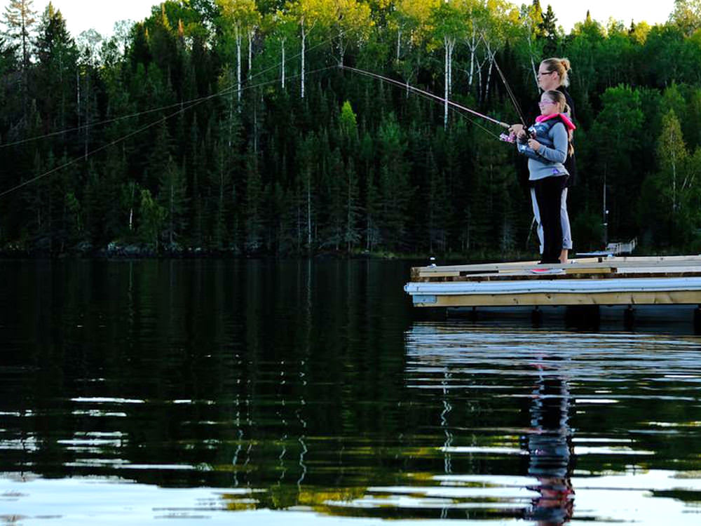 A mother and daughter fish off of a dock