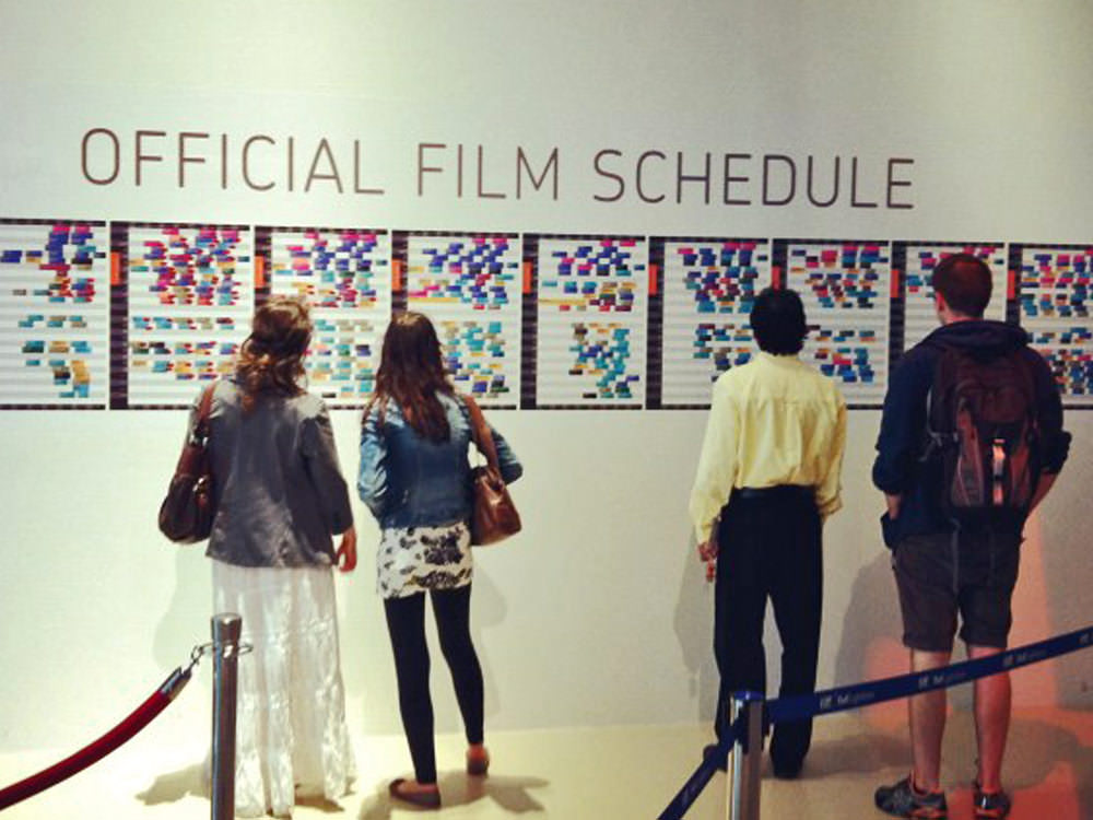Four people reviewing film schedules on a wall