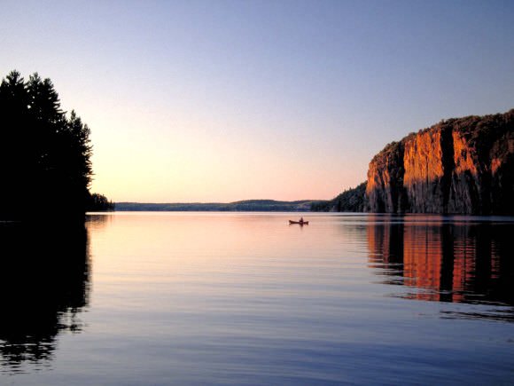 A boat on the lake beside a large rock