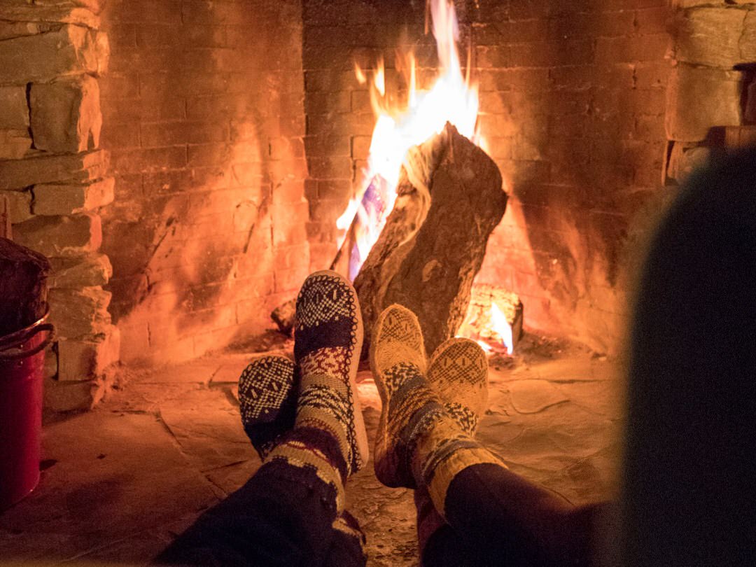 Close up of two pairs of feet in socks in front of a fire place
