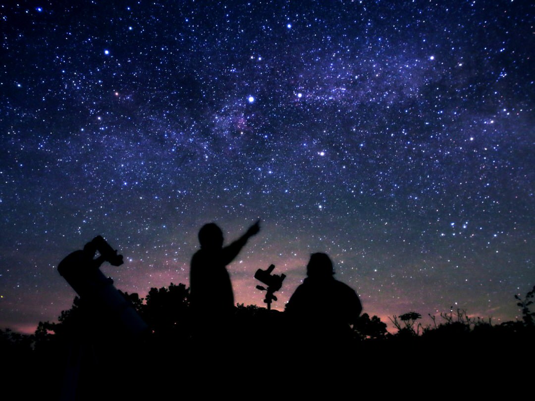 Silhouette of two people pointing and looking up at the stars