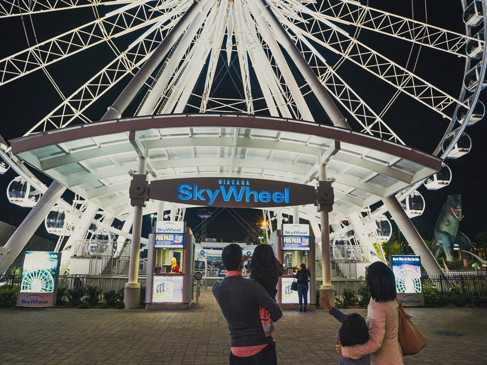 Ein Paar und ihre beiden kleinen Kinder stehen vor einem Riesenrad