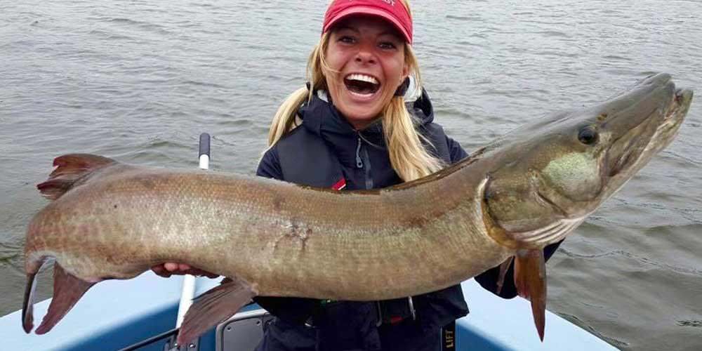 Ein professioneller Angler, Babs Kijewski hält einen großen Moschusfisch, der in einem Boot steht