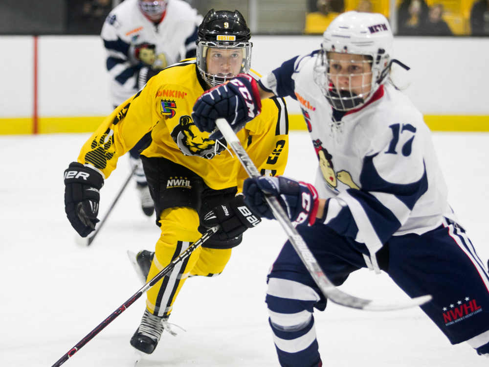 Two hockey players skate after the puck.