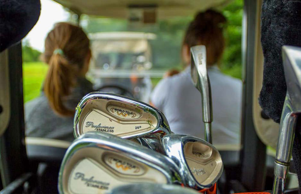 Zwei Frauen fahren mit einem Golfwagen über einen Golfplatz in Ontario