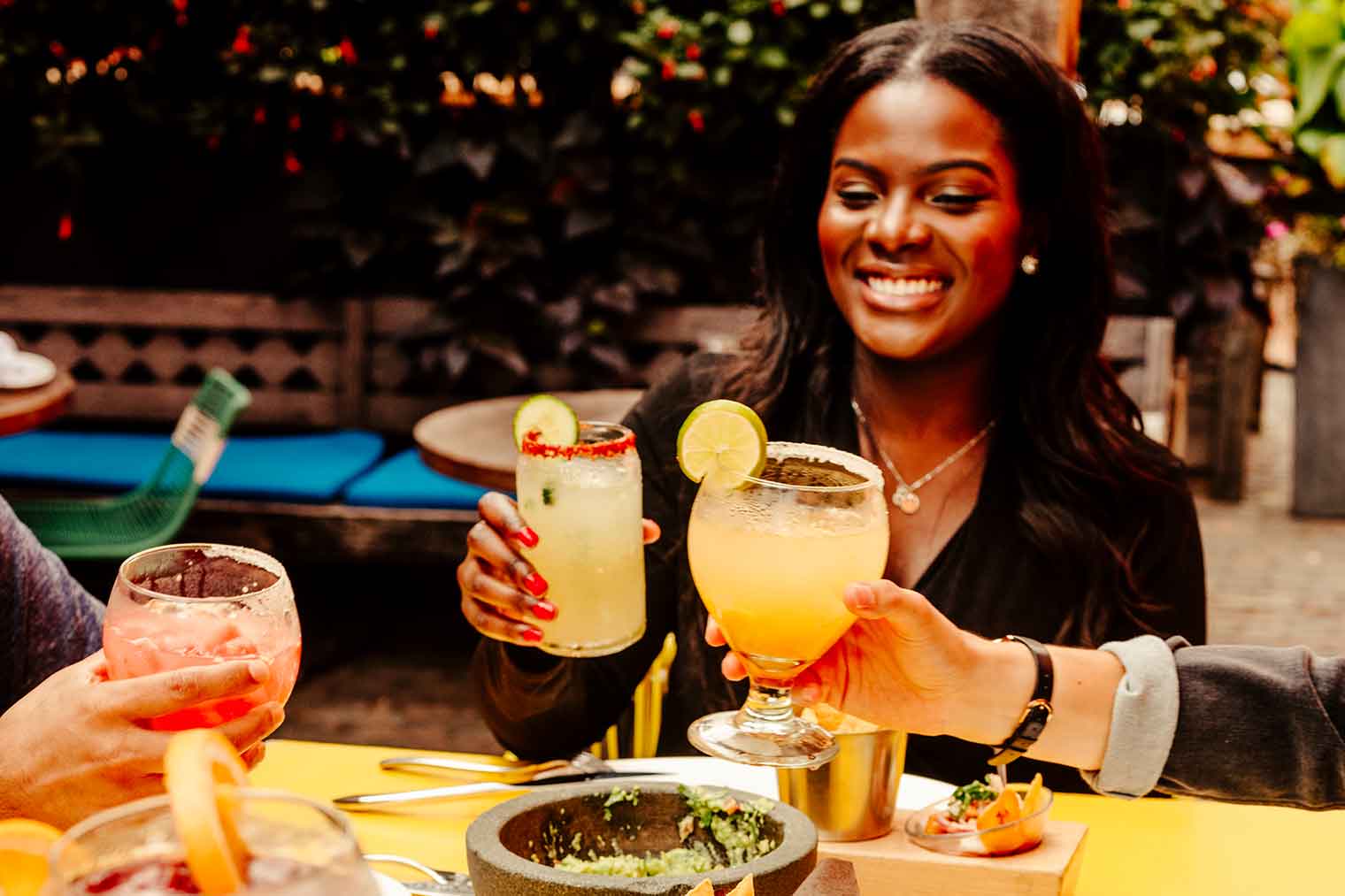 Tres personas disfrutando de bebidas juntas en el patio de un restaurante