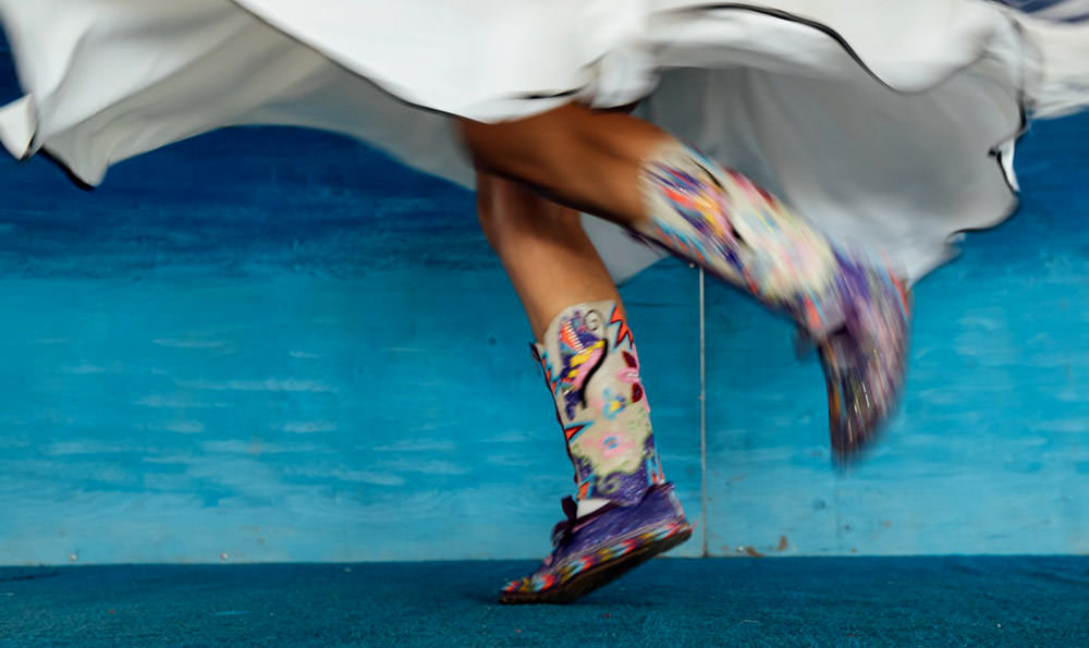 A twirling Indigenous dancer wearing colourful footwear and clothing.