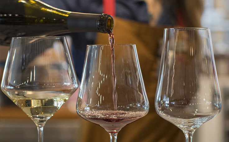 Woman pouring wine into three wine glasses.