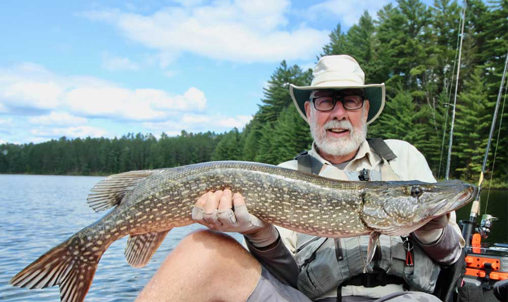 Ein Mann hält einen Hecht von einem Angelausflug in Muskoka hoch