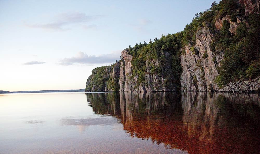 El reflejo de una enorme roca rugosa sobre aguas tranquilas