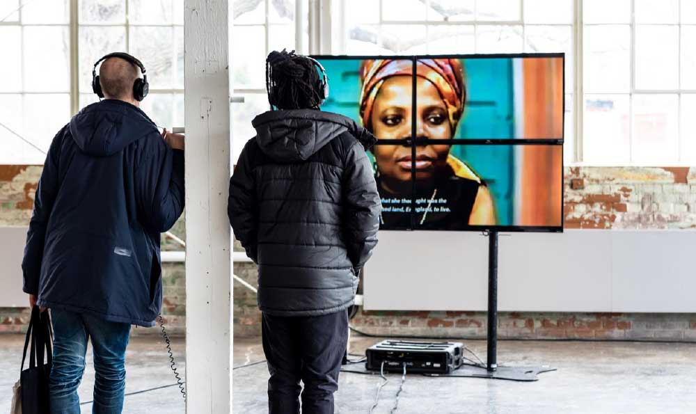 Galeriebesucher sehen sich True and Functional an, ein Video, das vom multidisziplinären Künstler Timothy Yanick Hunter erstellt wurde.