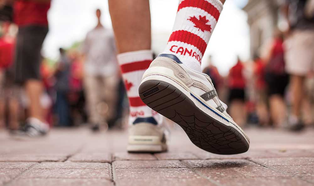 Primer plano de los pies de una persona con calcetines decorados con la bandera canadiense.
