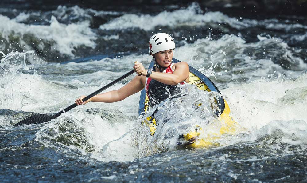 Eine Frau, die auf einem Wildwasserfloß die Stromschnellen reitet