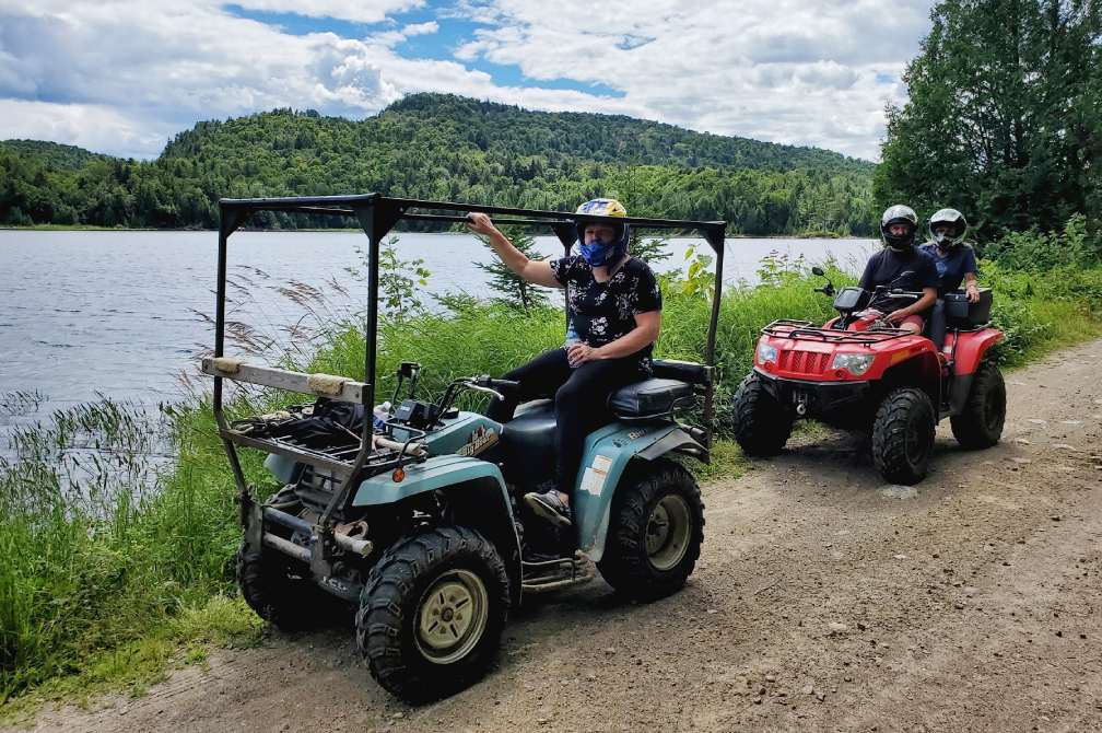 水域のそばの地形を走行する 2 台の ATV