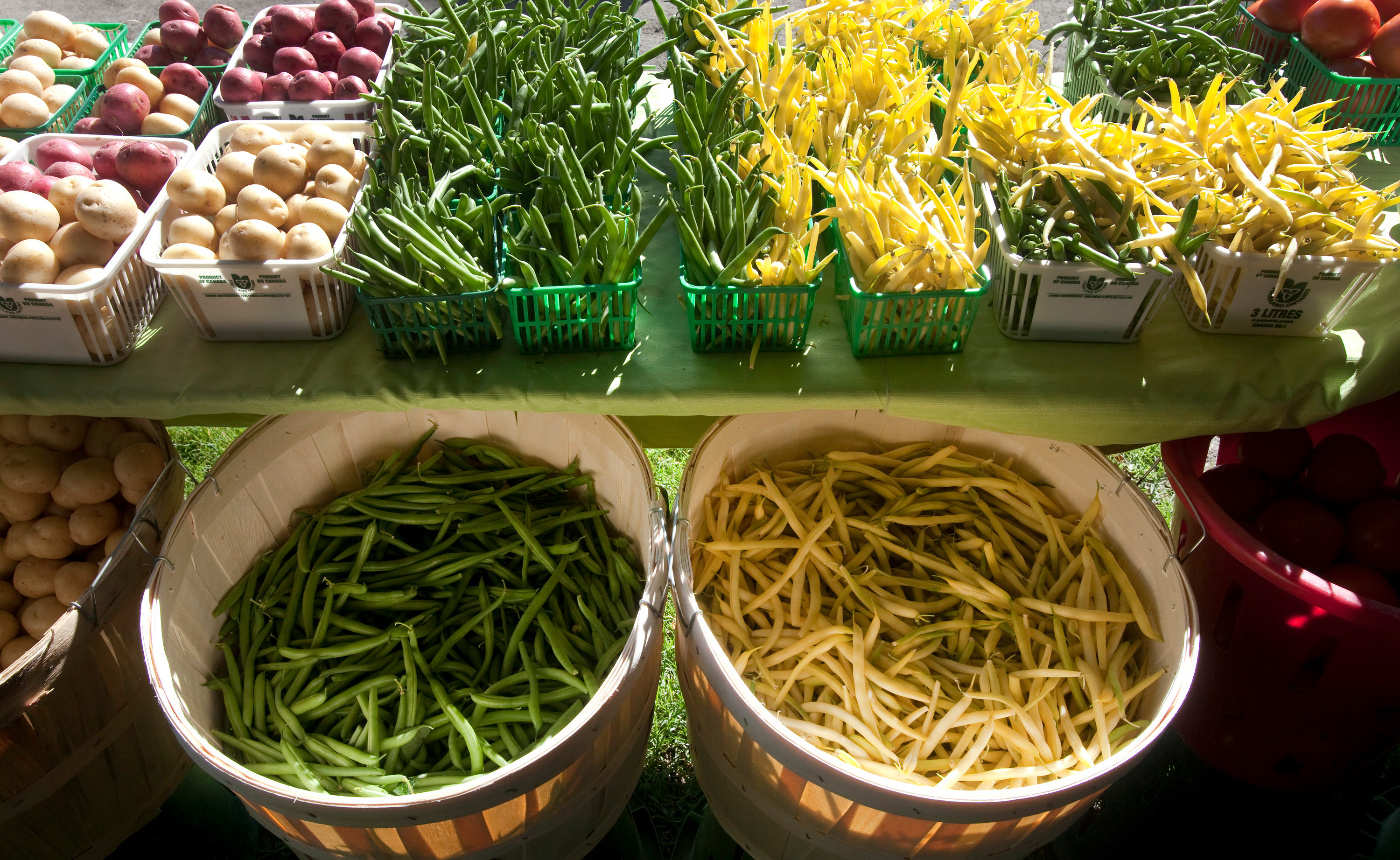 Cestas de patatas y frijoles frescos en un mercado de agricultores