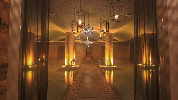 Ein unterirdischer Spa-Pool mit einem zentralen Weg und warmer Beleuchtung.
