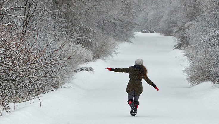 Une femme fait une promenade dans la neige dans les bois.