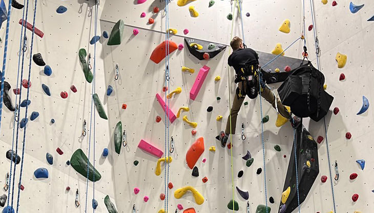 Un homme escalade un mur dans une installation d'escalade intérieure.