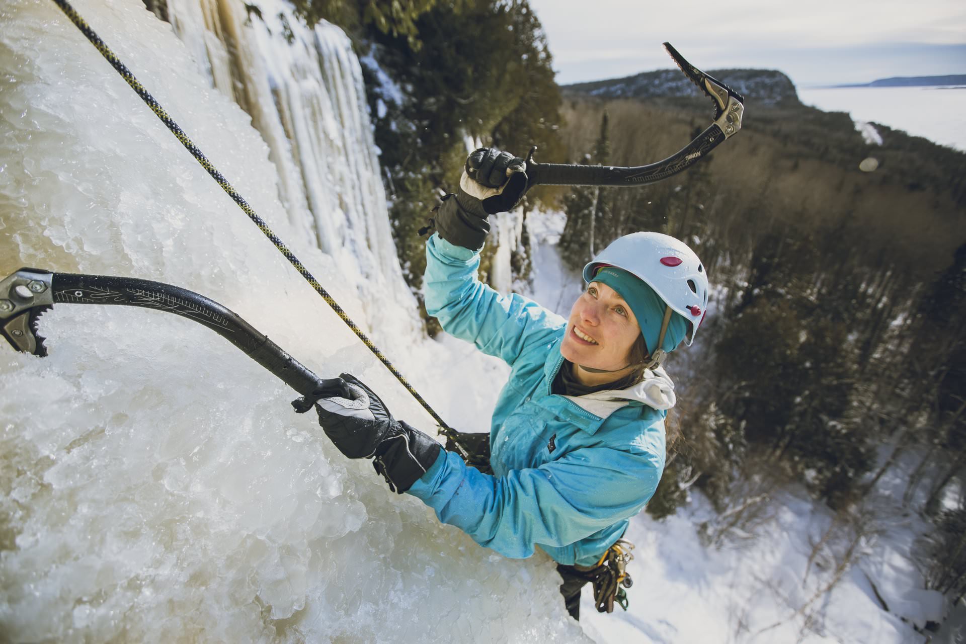 Una mujer escalando una cascada de hielo en Nipigon con piolets.