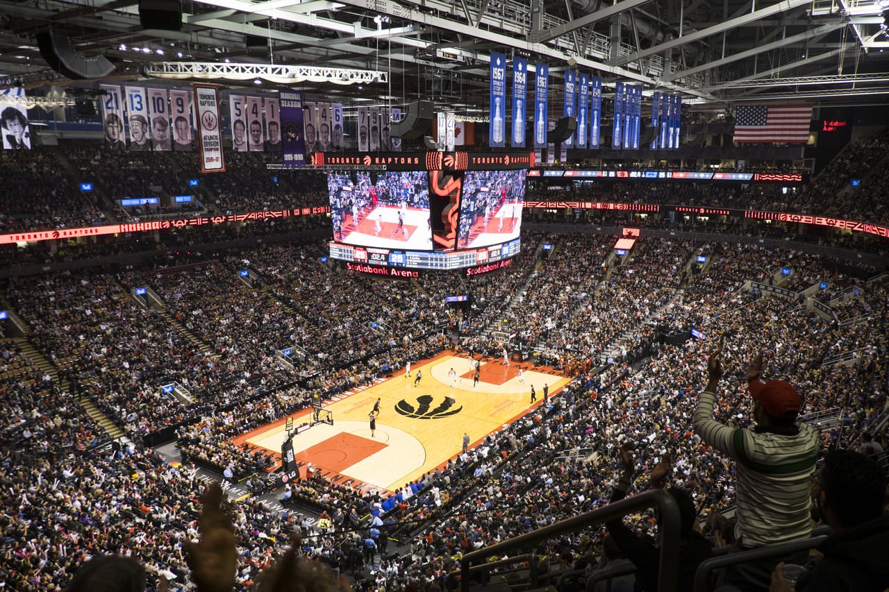 A sports arena full of people watching a basketball game.
