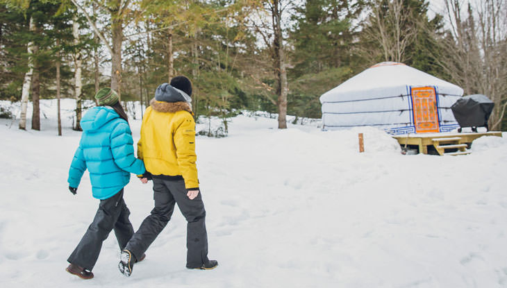 Una pareja camina hacia una yurta en invierno.